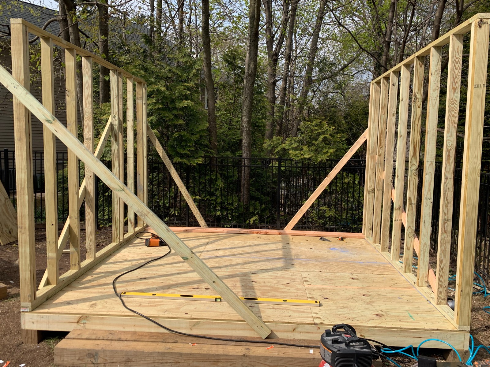 The wooden wall frames of a shed going up on a raised platform in a backyard