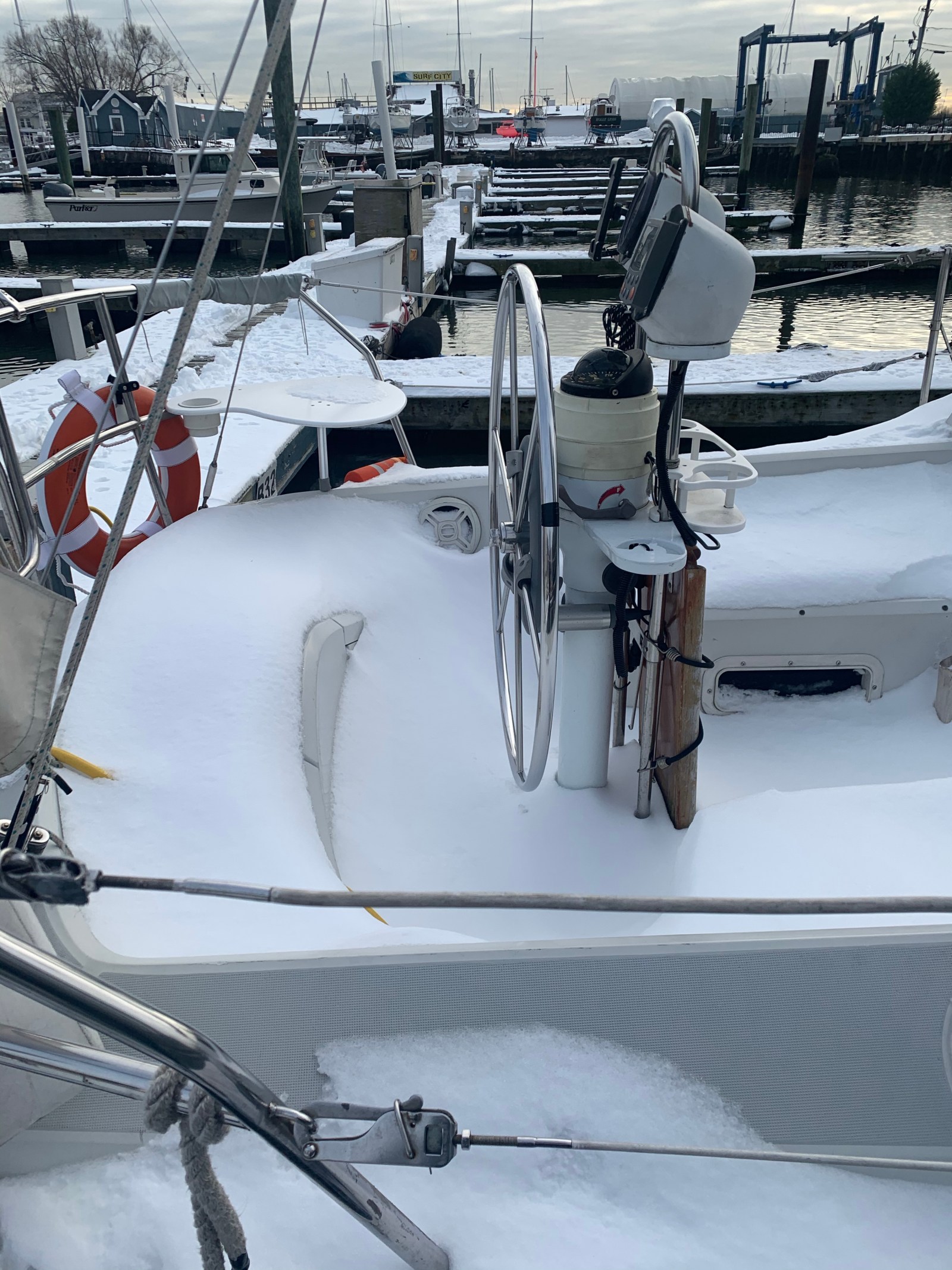 A sailboat cockpit and helm covered in snow at the marina
